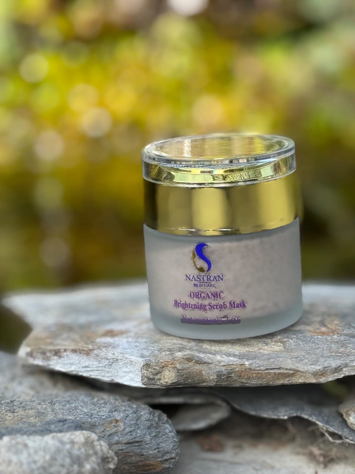 A jar of Organic Brightening Scrub Mask on a slate ledge outdoors